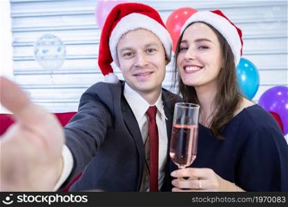 Happy new year 2022 concept,Selfie on smartphone of Happy couple holding the champagne glass in Christmas and New Year&rsquo;s Eve party Christmas tree background After finishing business work