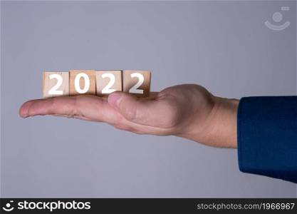 Happy New Year 2022 theme men&rsquo;s hands holding wooden cubes with the number 2022 on the palm. The concept of the new 2022.. Happy New Year 2022 theme men&rsquo;s hands holding wooden cubes with the number 2022 on the palm.