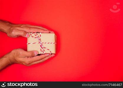 Happy New Year and Christmas 2020 or valentine day, top view hands with Brown gift box on red background with copy space for your text