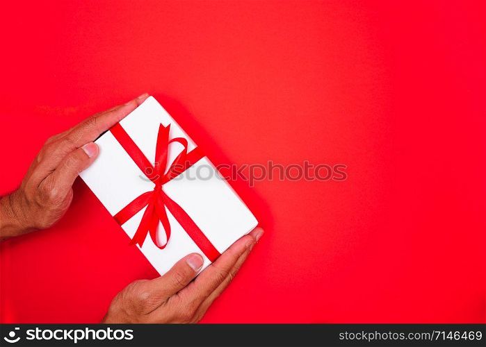 Happy New Year and Christmas 2020 or valentine day, top view hands with white gift box on red background with copy space for your text