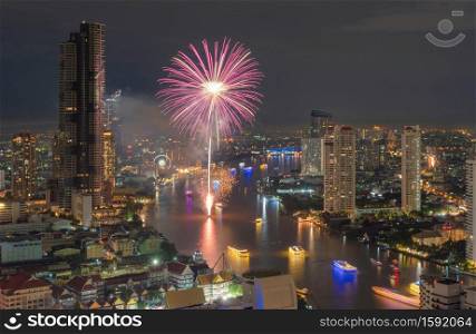 Happy New Year Fireworks Festival Event at Taksin bridge with Chao Phraya River in Bangkok, Thailand. Financial district and skyscraper buildings. Downtown skyline at night.