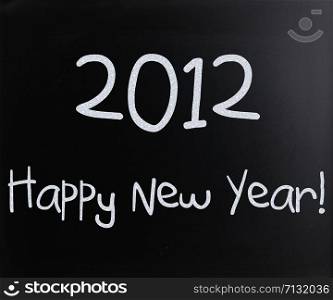 ""Happy New Year" handwritten with white chalk on a blackboard"