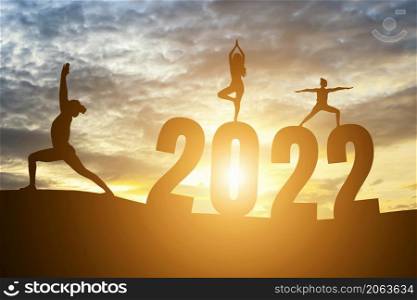 Happy New Year Numbers 2022, Silhouette woman practicing yoga early morning sunrise over the horizon background, Health and Happy new year concept.