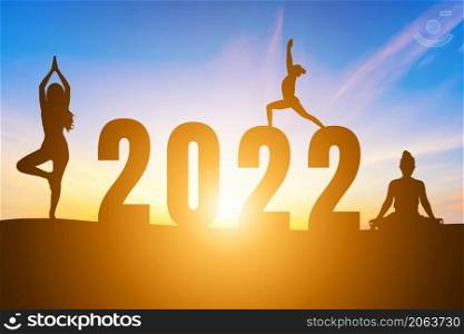 Happy New Year Numbers 2022, Silhouette woman practicing yoga early morning sunrise over the horizon background, Health and Happy new year concept.