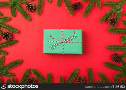 Happy new year or christmas day top view flat lay fir tree branches and gift box, decoration on red background with copy space for your text
