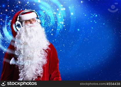 Happy New Year. Santa Claus wearing headphones and enjoying music