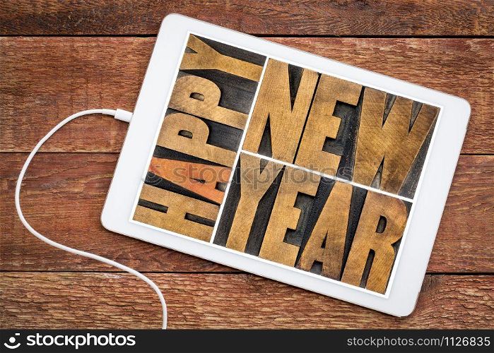 happy new year typography in vintage letterpress wood type on a digital tablet, greeting card concept