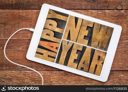 happy new year typography in vintage letterpress wood type on a digital tablet, greeting card concept