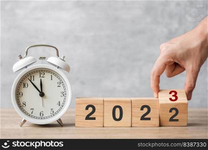 Happy New Year with vintage alarm clock and hand flipping 2022 change to 2023 block. Christmas, New Start, Resolution, countdown, Goals, Plan, Action and Motivation Concept