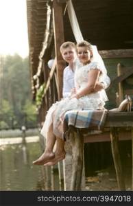 Happy newly married couple sitting next to river at forest