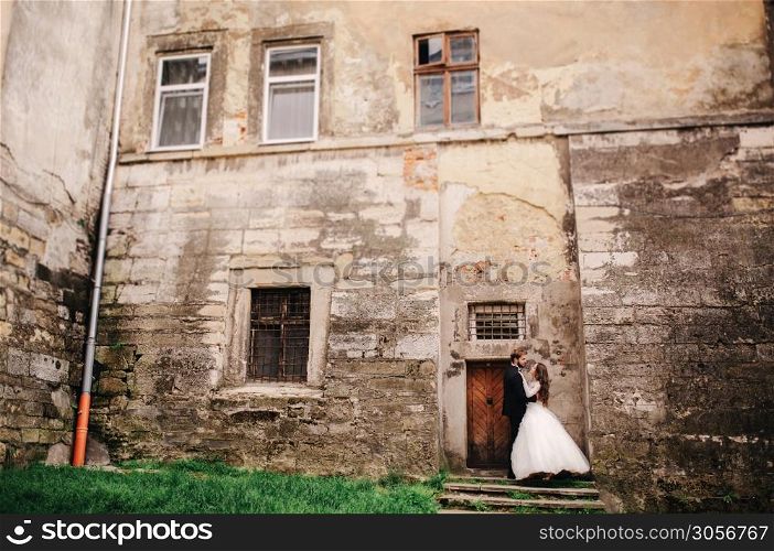 Happy newlywed couple hugging and kissing in old European town street, gorgeous bride in white wedding dress together with handsome groom. wedding day. Happy newlywed couple hugging and kissing in old European town street, gorgeous bride in white wedding dress together with handsome groom. wedding day.