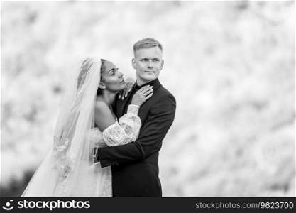 Happy newlyweds against the backdrop of sunny evening foliage, the guy looks into the distance, the girl looks at the guy a. Happy newlyweds against the backdrop of sunny evening foliage, the guy looks into the distance, the girl looks at the guy