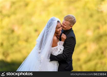 Happy newlyweds hugging against the backdrop of sunny evening foliage a. Happy newlyweds hugging against the backdrop of sunny evening foliage