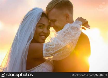Happy newlyweds hugging in the rays of the setting sun