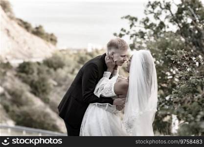 Happy newlyweds kiss against the backdrop of a beautiful mountain landscape, sepia