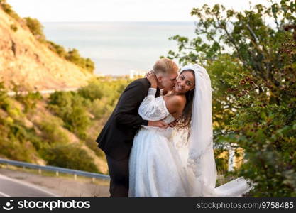 Happy newlyweds kiss against the backdrop of a beautiful mountain landscape, the girl fervently turns away from the guy