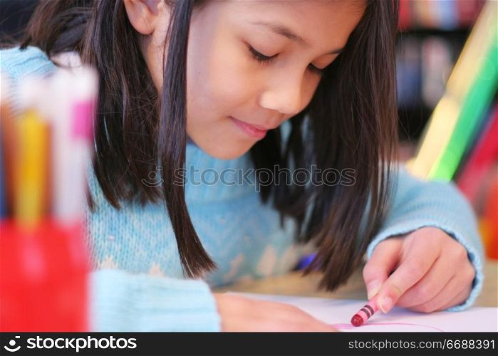 Happy nine year old girl drawing.