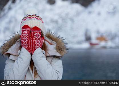 happy norwegian girl pose for the camera in red mittens with a Norwegian pattern. Lofoten islands. Norway
