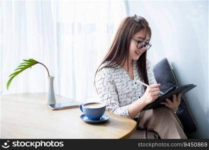 Happy of asian freelance people business female casual working with Draw or taking note on digital tablet with electronic pen for browsing internet chatting and blogging with coffee cup in coffee shop