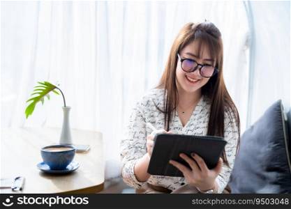 Happy of asian freelance people business female casual working with Draw or taking note on digital tablet with electronic pen for browsing internet chatting and blogging with coffee cup in coffee shop