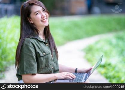 Happy of asian freelance people business female casual working with laptop computer outdoors at sunny summer day in park background,education and remote working communication concept