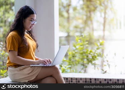 Happy of asian freelance people business female casual working with laptop computer sitting on a bench in coffee shop like the background,communication concept