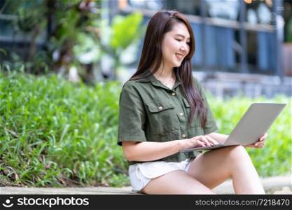 Happy of asian freelance people business female casual working with laptop computer outdoors at sunny summer day in park background,education and remote working communication concept