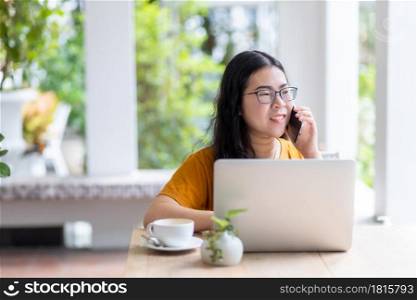 Happy of asian freelance people business female hold pick up smartphone casual working with laptop computer with coffee cup in coffee shop like the background,communication concept