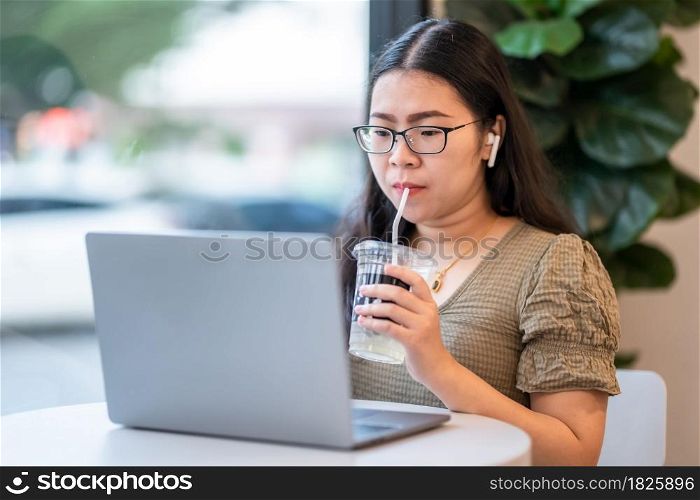 Happy of asian freelance people Businesswoman wearing wireless earphones with sucking coffee working with laptop computer,Notebook and smartphone at the cafe,Business Lifestyle communication