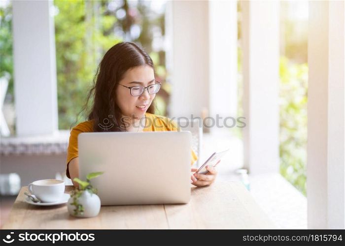 Happy of asian freelance people Businesswoman writing message on smartphone casual working with laptop computer with a coffee cup mug at the cafe,Business Lifestyle