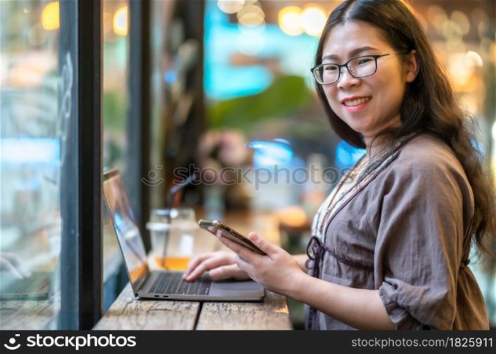 Happy of asian freelance people Businesswoman writing message on smartphone casual working with laptop computer with a coffee cup mug at the cafe,Business Lifestyle