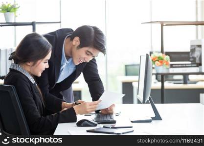 Happy of businesswoman and businessman partners discussing positive adult business working together with computer on wooden table and ideas at meeting in office background.