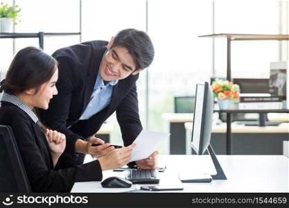Happy of businesswoman and businessman partners discussing positive adult business working together with computer on wooden table and ideas at meeting in office background.