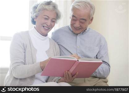 Happy old couple looking at photo album together