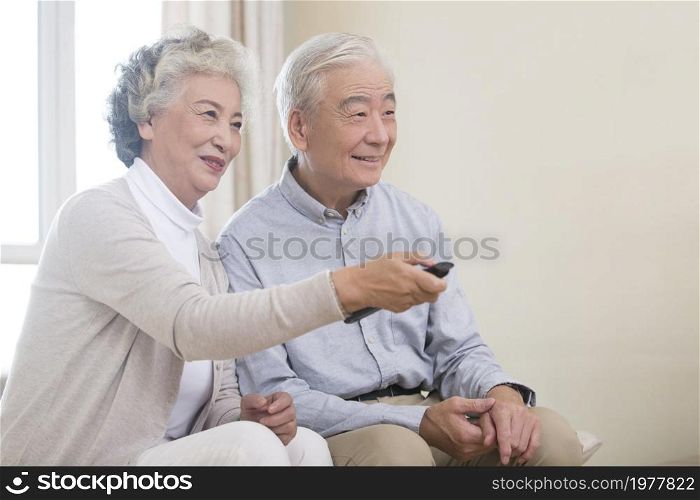 Happy old couple watching TV at home