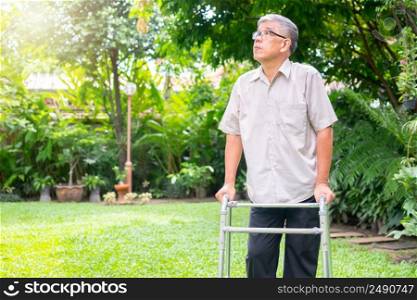 Happy old elderly Asian man uses a walker and walks in the backyard.  Concept of happy retirement With care from a caregiver and Savings and senior health insurance