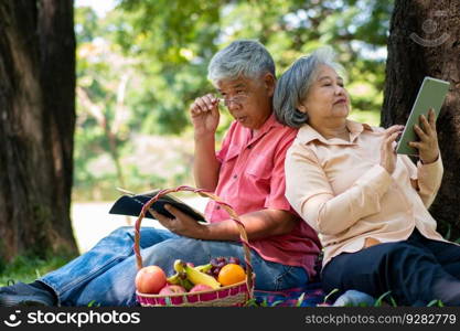 Happy old elderly couple spouses relaxing and sitting on a blanket in the park and sharing few precious memories. Senior couple having great time together on a picnic. concept of mature relationships