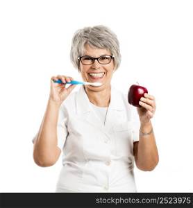 Happy old female doctor holding a apple and a toothbrush isolated on white