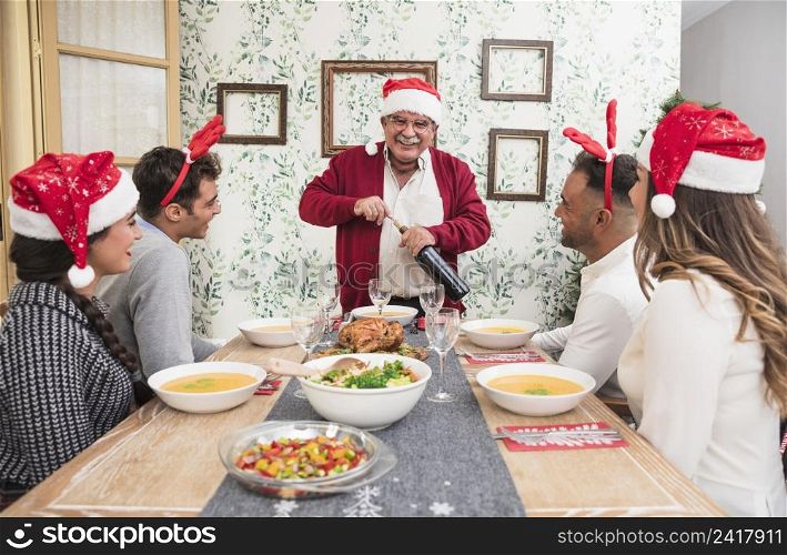 happy old man opening wine bottle festive table