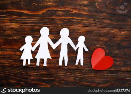 Happy paper cut family holding hands on a brown wooden background with red heart. Happy paper cut family holding hands on a brown wooden background with red heart.