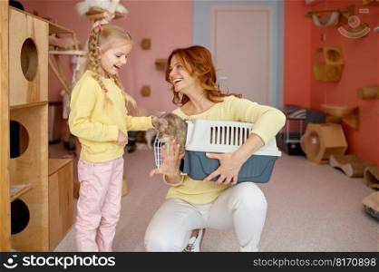 Happy parent and child choosing new pet in animal cat shelter. Portrait of smiling mother holding cage with kitten and curious kid looking at fluffy feline. Happy parent and child choosing new pet in animal cat shelter