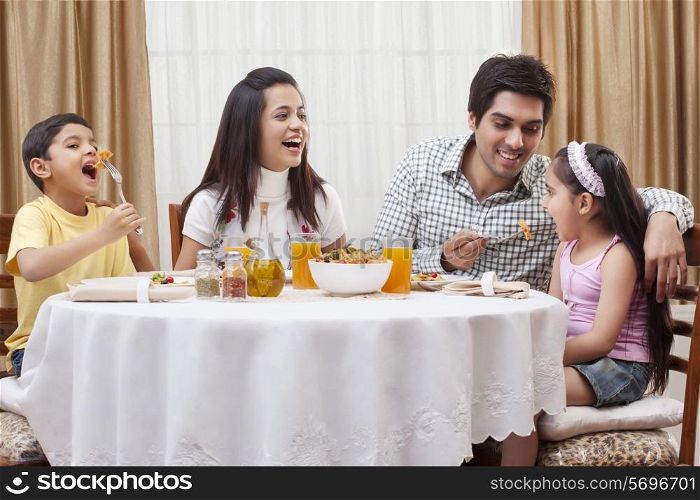 Happy parents and children eating pizza together at restaurant
