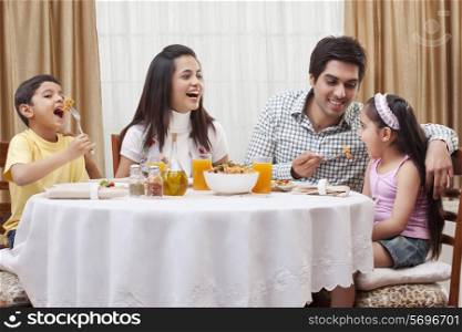 Happy parents and children eating pizza together at restaurant