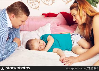 happy parents and cute baby sleeping on bed. Happy Family