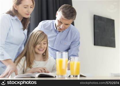 Happy parents assisting daughter in homework at home