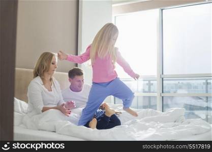 Happy parents looking at playful children in bedroom