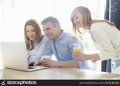 Happy parents with daughter using laptop at home