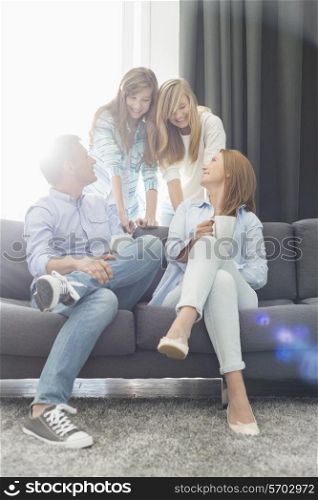 Happy parents with daughters spending quality time in living room