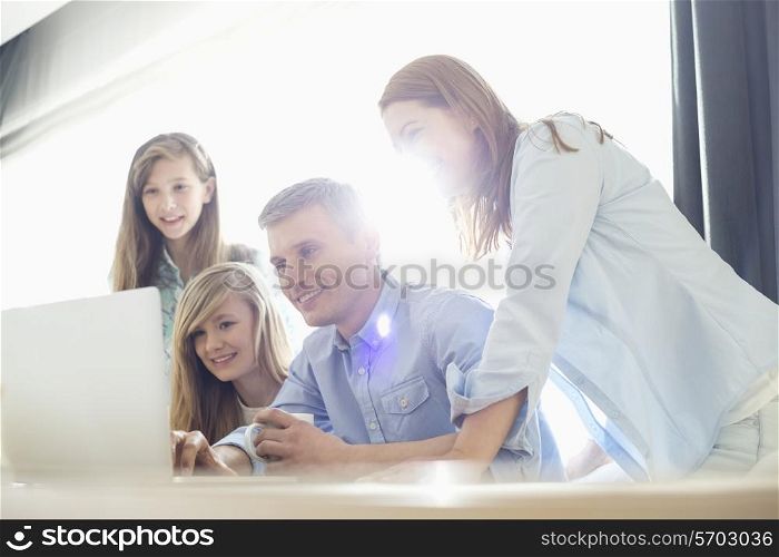 Happy parents with daughters using laptop at home