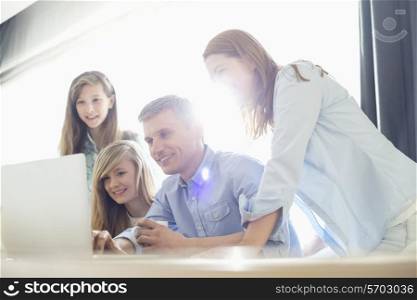 Happy parents with daughters using laptop at home